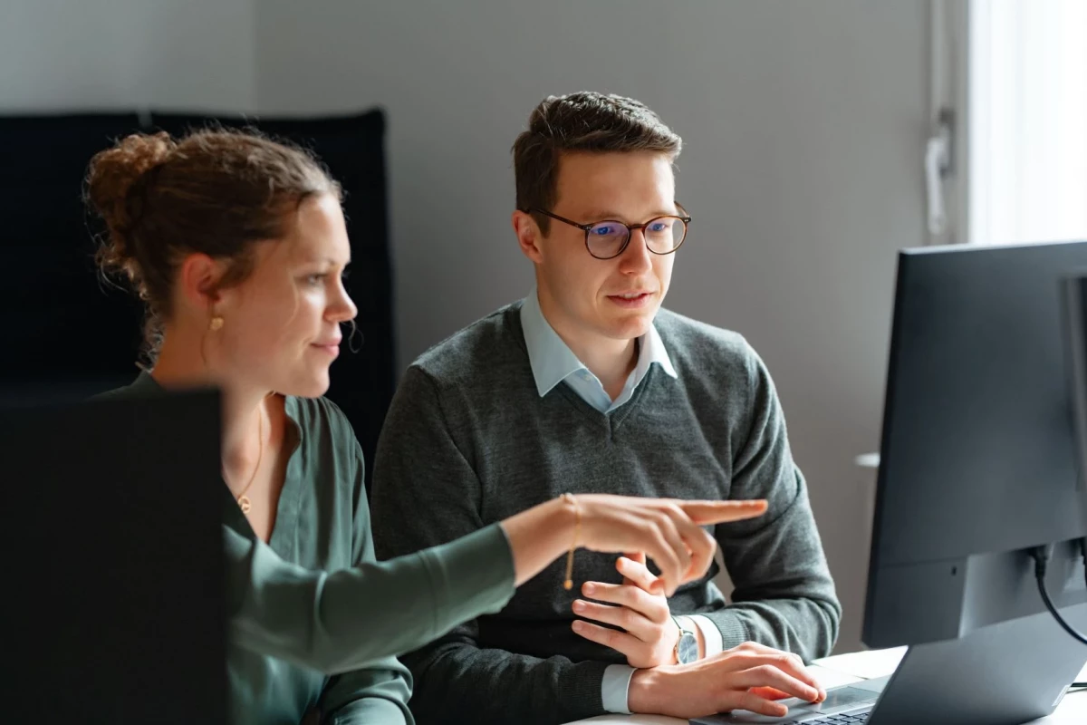 A man and woman are intently observing a computer screen together, engaged in discussion or analysis.
