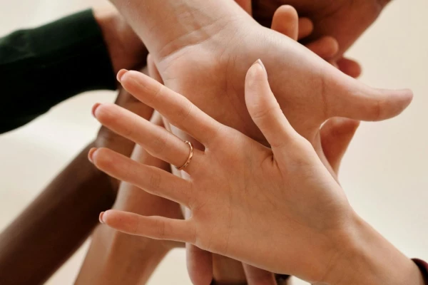 A diverse group of individuals standing together, their hands joined in unity and solidarity.